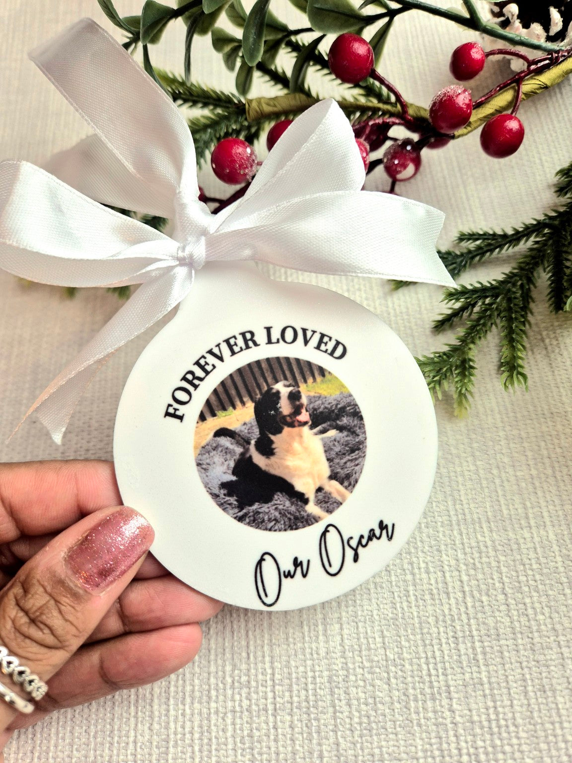 White round memorial ornament with a pet photo, white ribbon, and the words Forever Loved Our Oscar